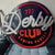 Decorative sign for 'Derby Club Gaming Parlor' on a chair outdoors.
